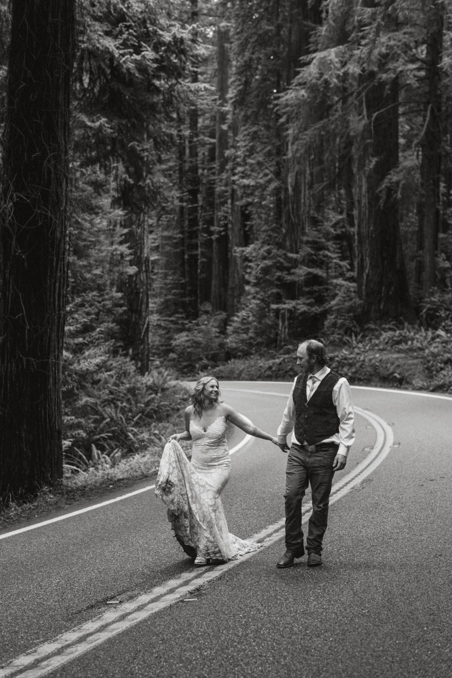 bride and groom walking on the road amongst the redwoods